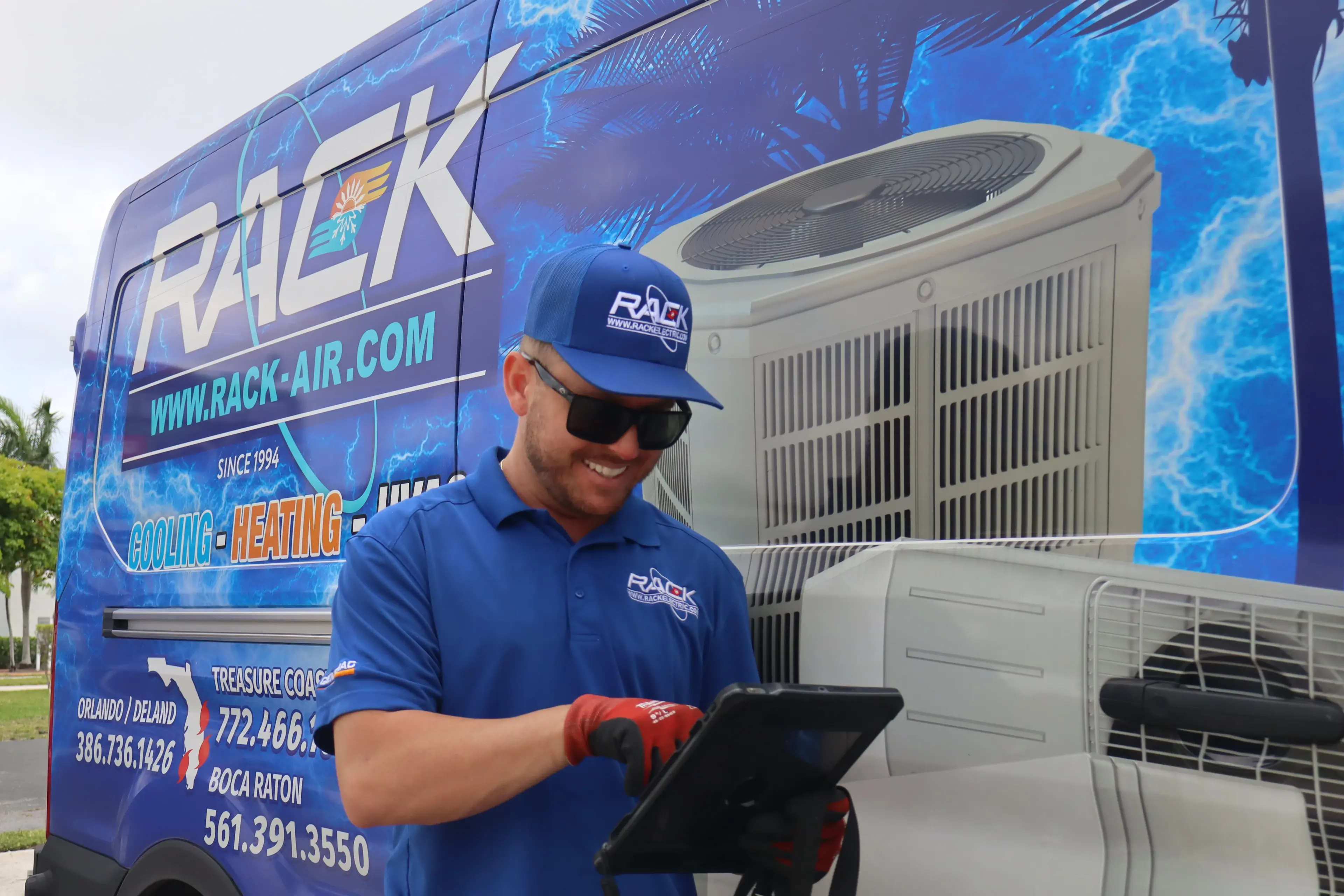 Rack Air technician reviewing job details on a tablet by the van