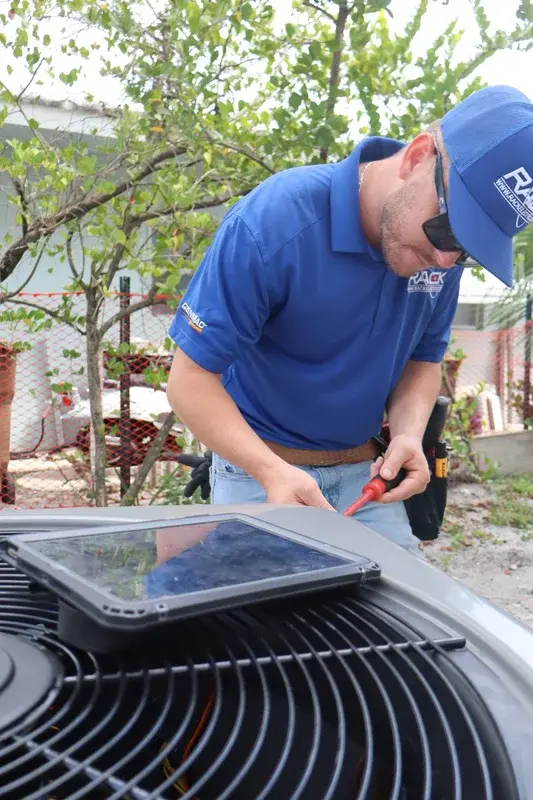 Rack Air technician servicing an outdoor heat pump unit in DeLand FL