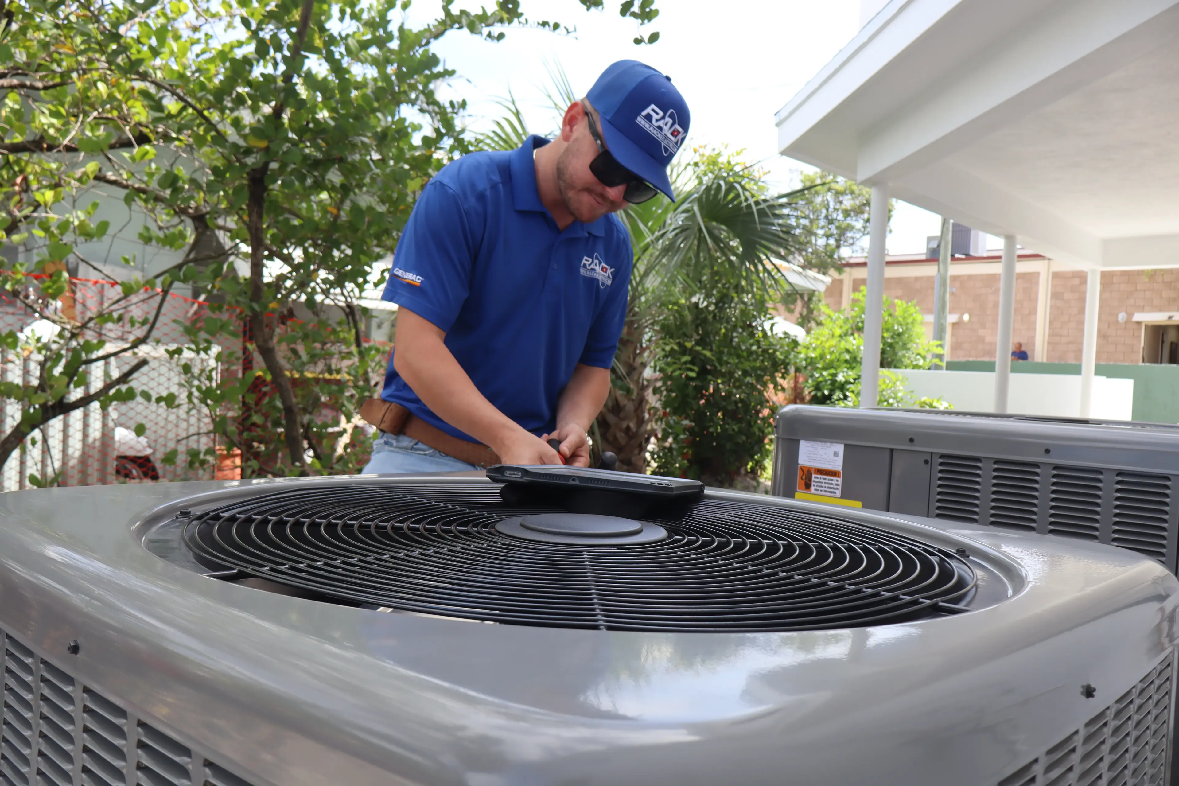 Rack Air technician rinsing salt deposits off a corroded condenser coil at a beachside Daytona home